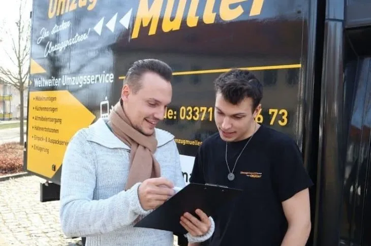 umzugshelfer bespricht umzug mit kollegen vor umzugswagen